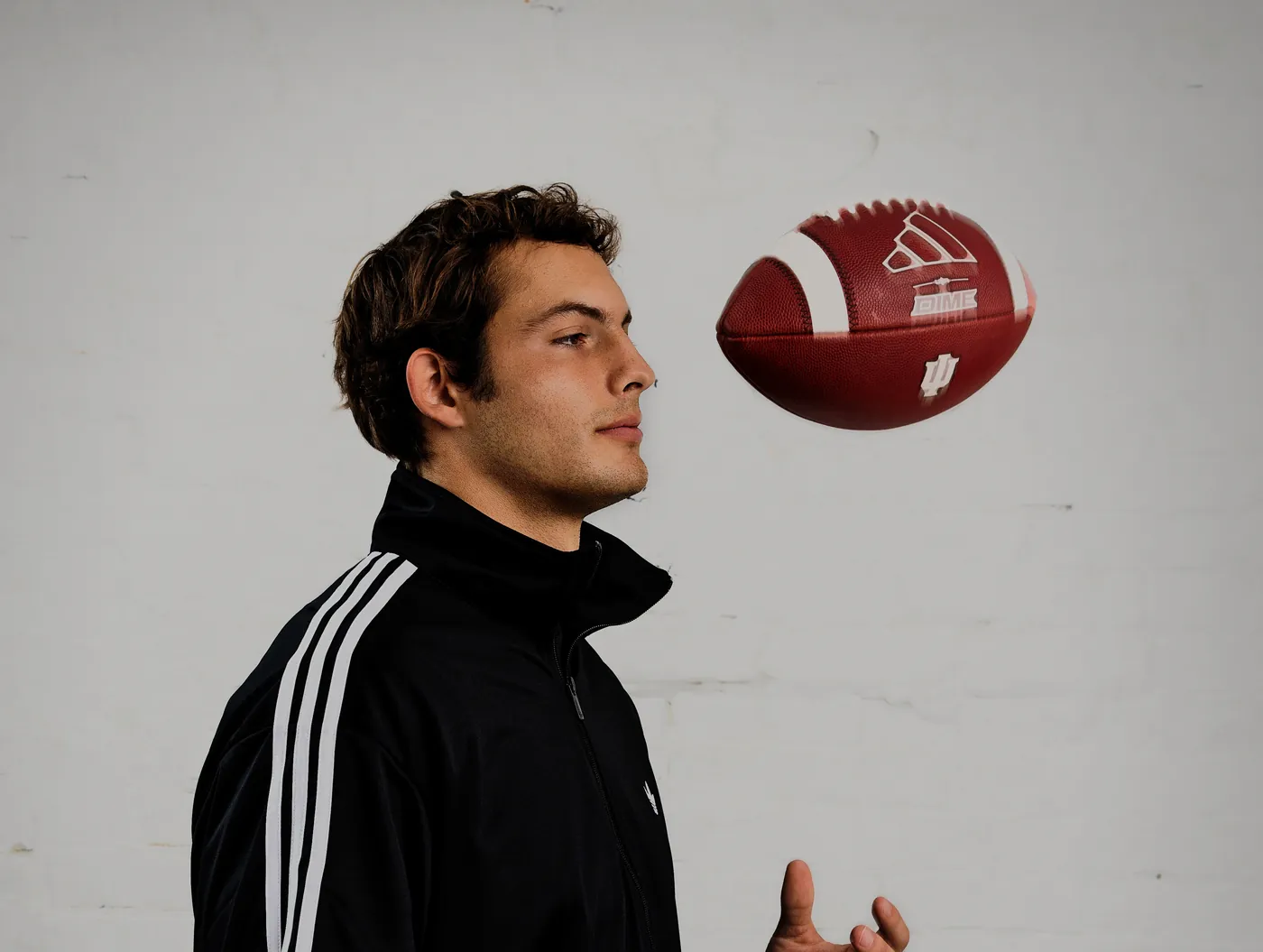 An Indiana football player in profile with a ball in the air, shot by MUUS for adidas US Football