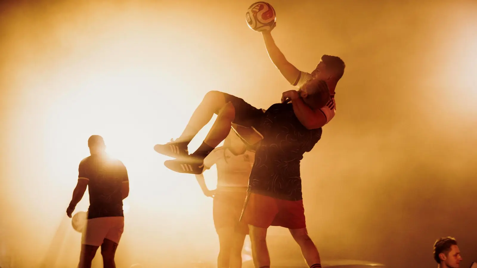 A freestyler lifted mid air in backlit haze at the WC26 Away Kit launch