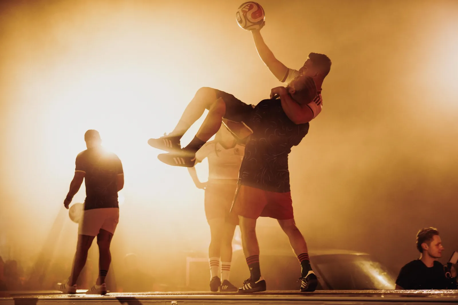 A freestyler lifted mid air in golden haze at the adidas WC26 Away Kit launch, Lower Grand, Los Angeles