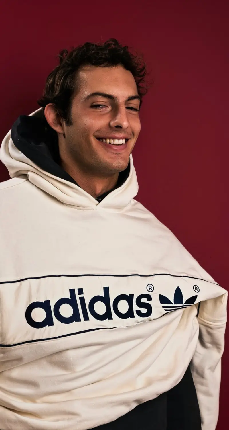Charlie Becker laughing in the cream adidas hoodie on red