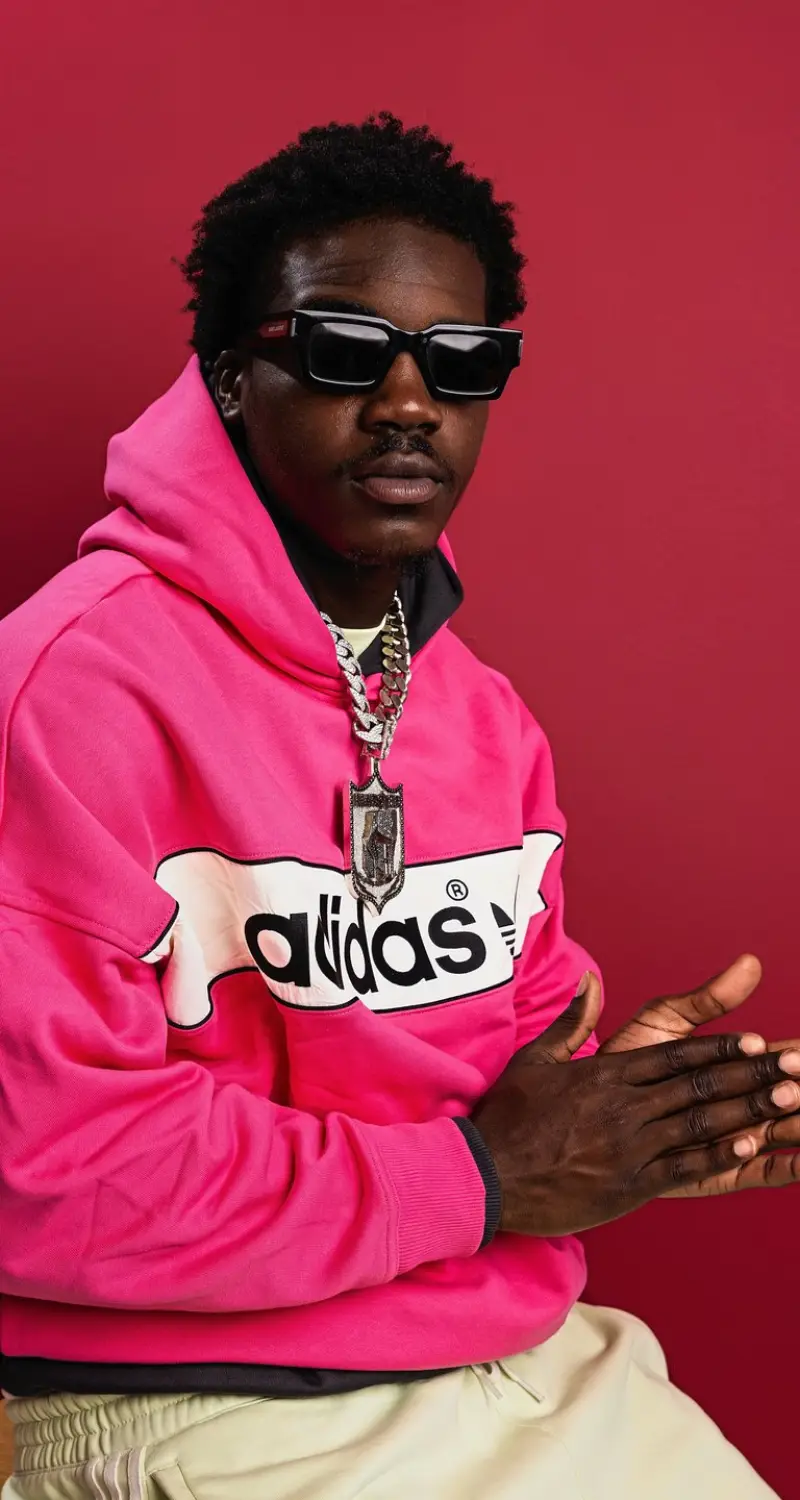 Nick Marsh seated in the pink adidas hoodie and shades on red