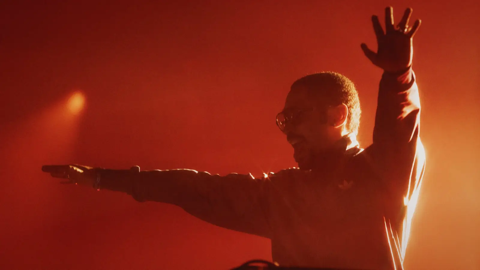 A DJ with arms out in red haze at the adidas WC26 Away Kit launch
