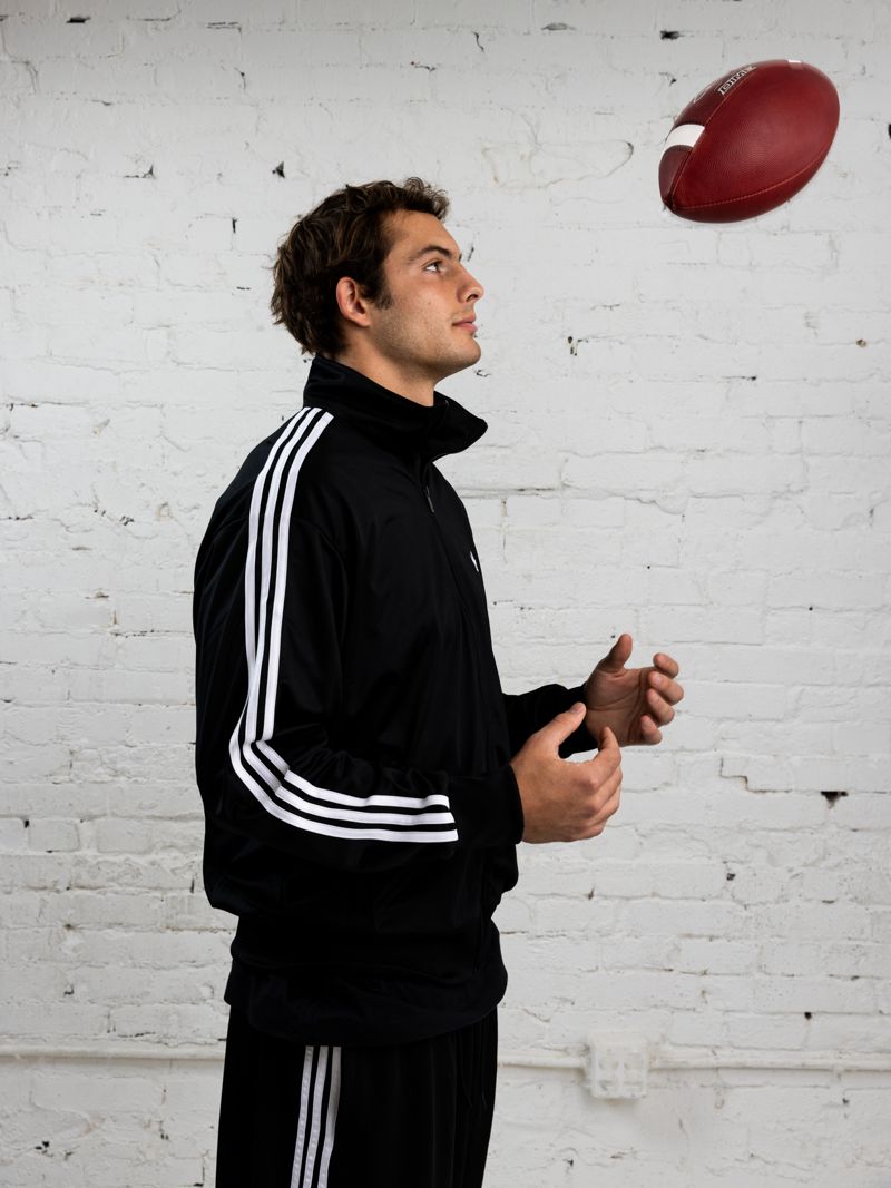 Charlie Becker in an adidas track suit looking up at a tossed football