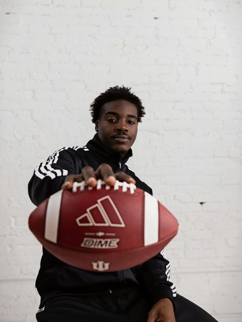 Nick Marsh seated, holding an adidas football out to camera