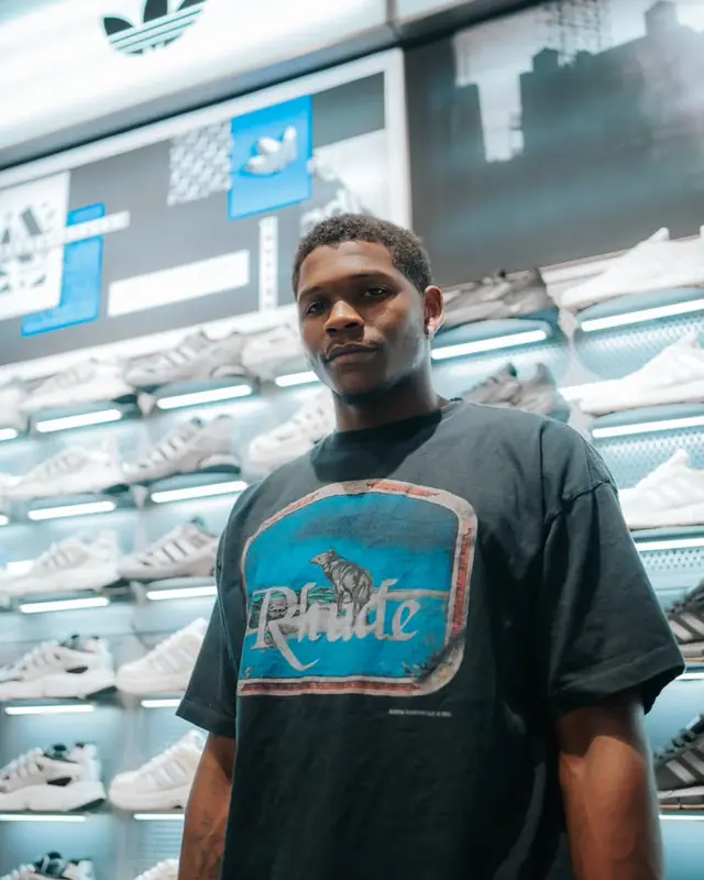 An athlete in a JD Sports store in front of the sneaker wall